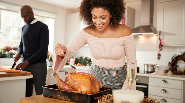 Woman putting liquid on turkey