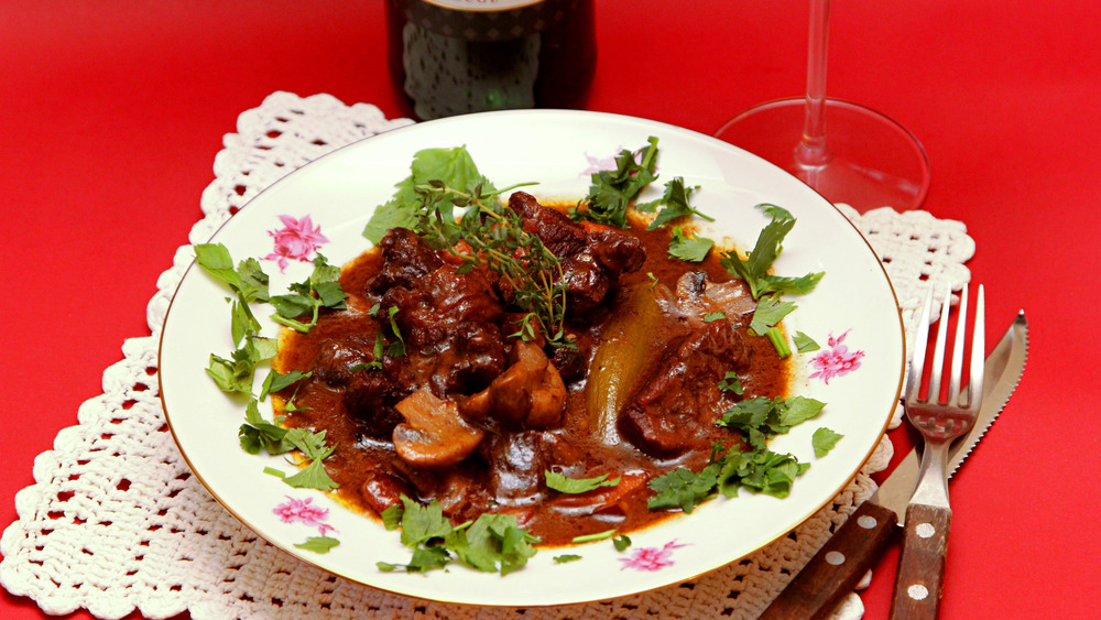 Beef stew on a white plate with red background