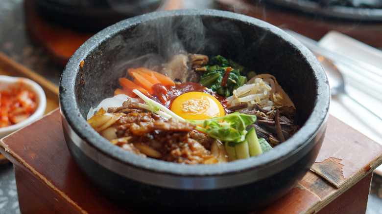 Stone pot filled with veggies and egg and steam rising from top