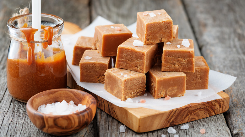 Stack of caramel candies alongside jar of caramel