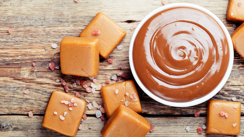 Caramel squares next to bowl of melted caramel