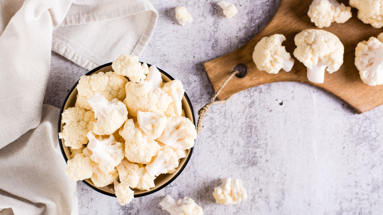 raw cauliflower in bowl and on board