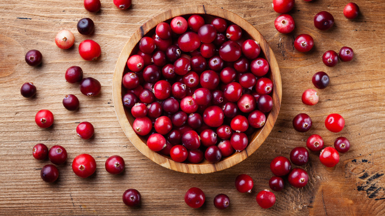 Cranberries in wooden bowl on wooden surface