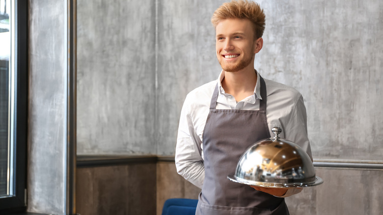 Waiter holding plate covered with cloche