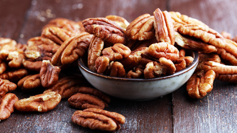 shelled pecans in small bowl on wood table