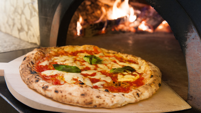 A pizza going into a stone oven