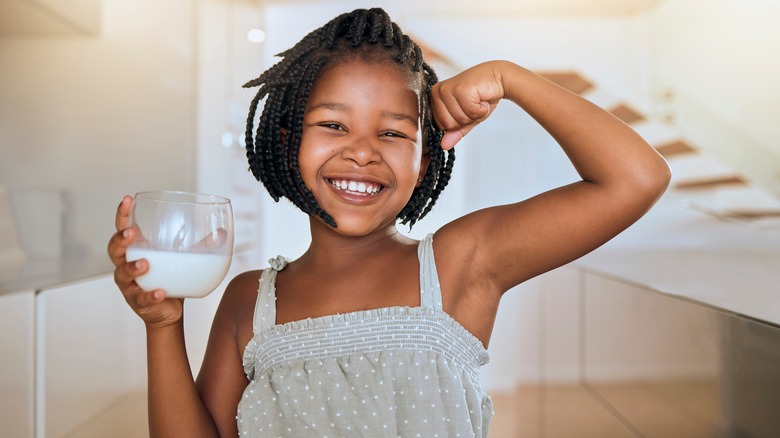 Girl flexing and holding glass of milk