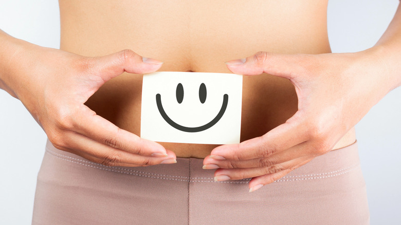 woman holding smiley face in front of stomach