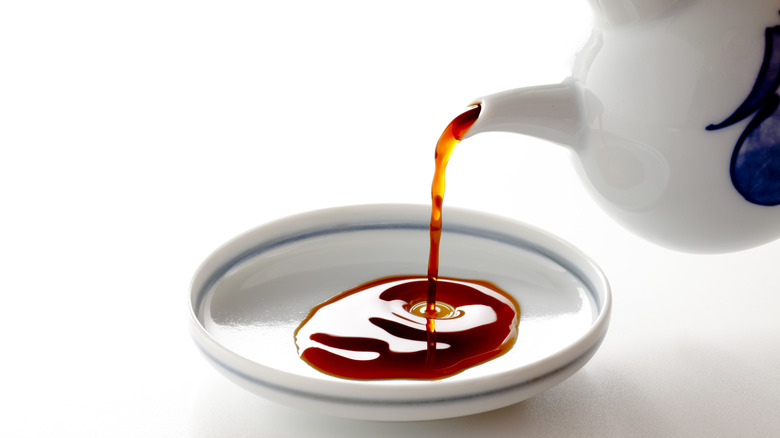 Pouring soy sauce from a white teapot into a white bowl