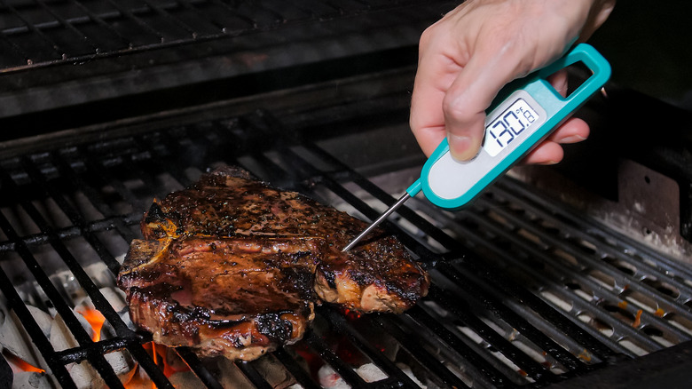 person putting thermometer in steak 