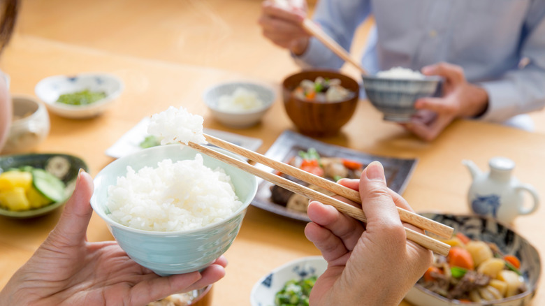 two people eating rice and Japanese food