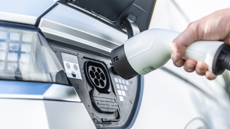 A person plugs a charger into their electric vehicle