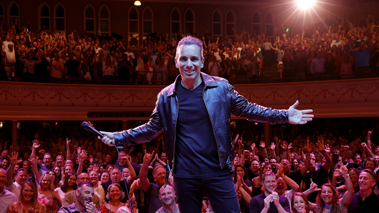 Sebastian Maniscalco on a stage with audience behind him