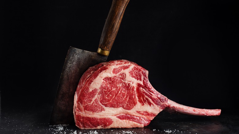 Raw bone-in ribeye with cleaver