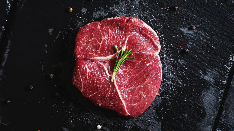 Uncooked tenderloin and garnish on black surface