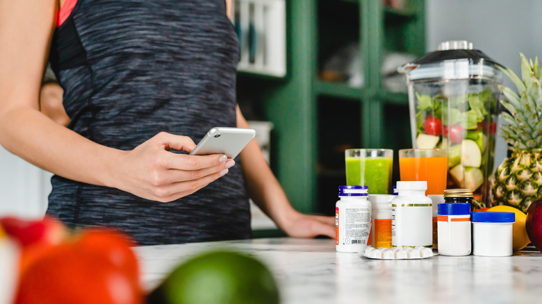 woman pills phone making smoothies