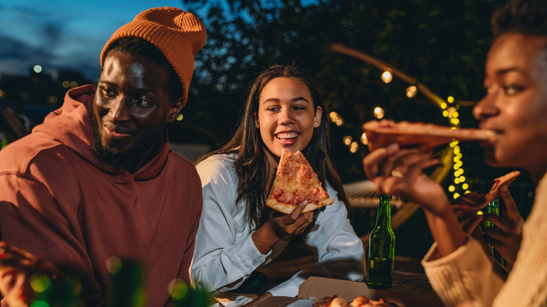 Three people eating pizza