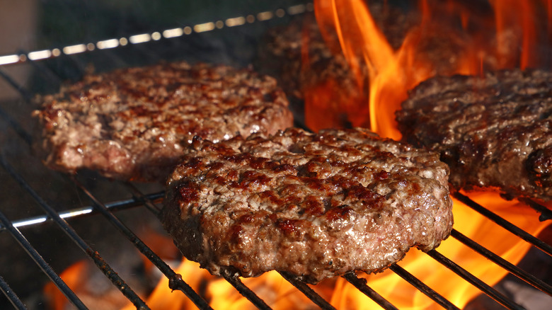 Burgers on grill over flame