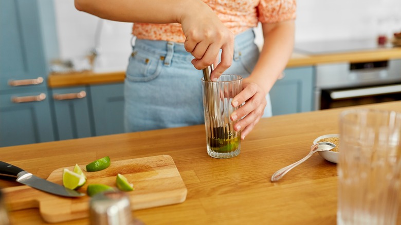 Person muddling lime in a glass