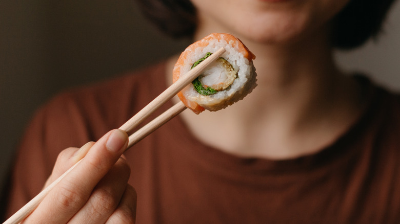 woman picking up sushi roll