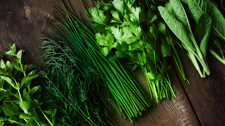 fresh herbs like chives, thyme, and parsley on wood cutting board