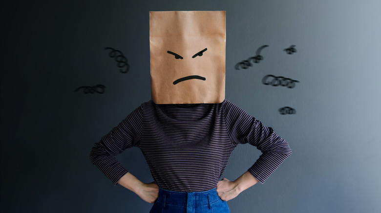 Person wearing angry-face paper bag