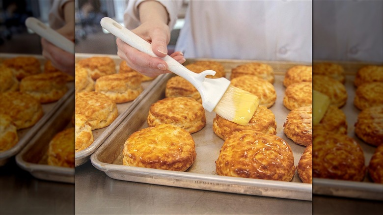 Baker spreading butter on biscuit