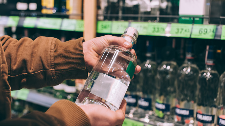 holding vodka bottle in store