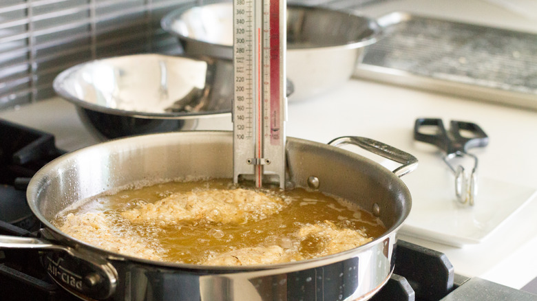 chicken fried in pan with thermometer