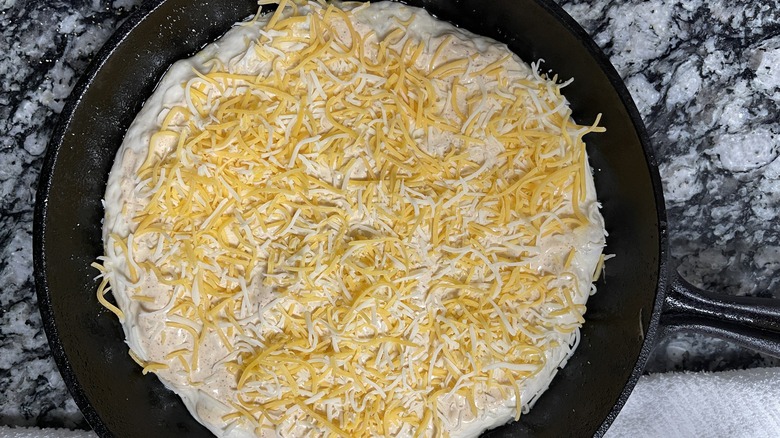 Mexican cheese blend on pizza dough in skillet