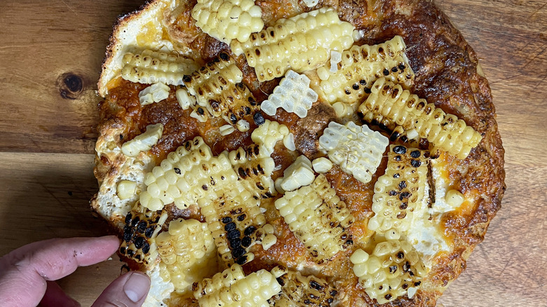 topping cheesy pizza with seared corn kernels