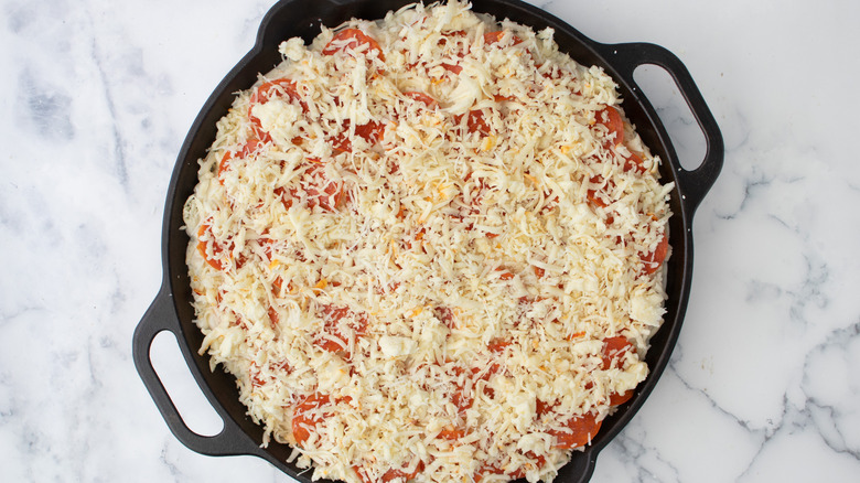 assembling cheesy pizza skillet