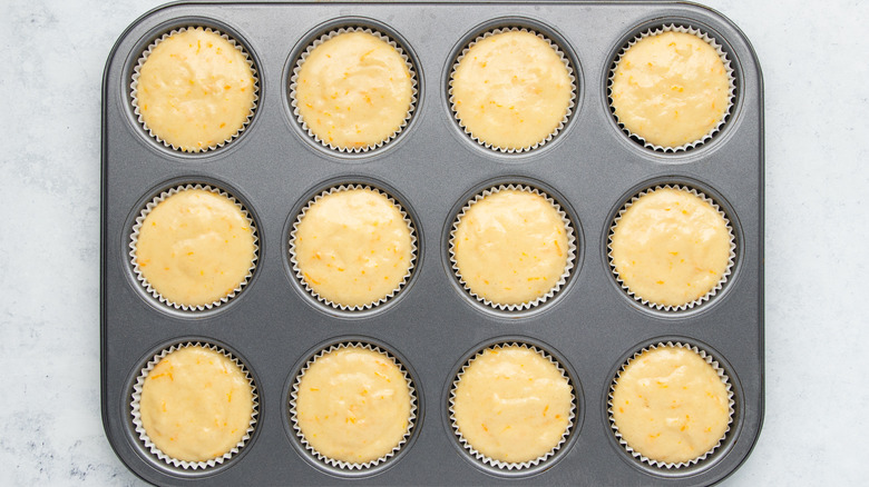 orange muffin batter in muffin tin