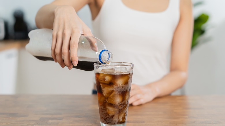 Woman pouring soda into glass 