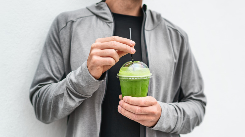 Man holding green smoothie cup