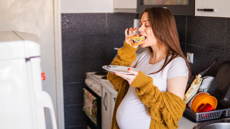 pregnant woman eating a sandwich