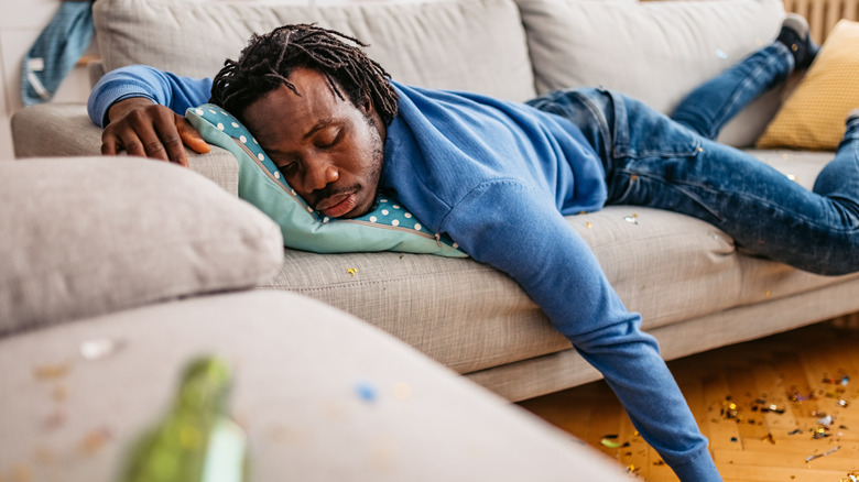 young man asleep on the couch suffering a hangover