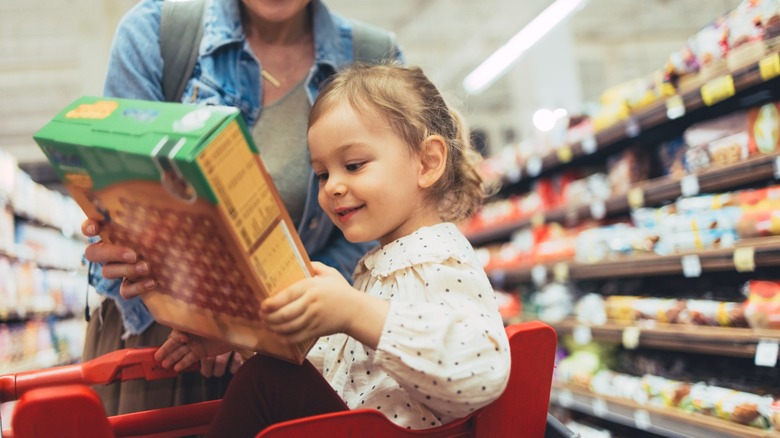 smiling child holding cereal box