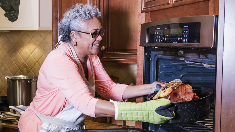 lady taking pineapple ham out of the oven