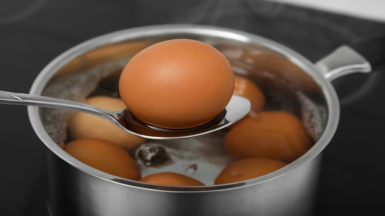 Egg on spoon above saucepan