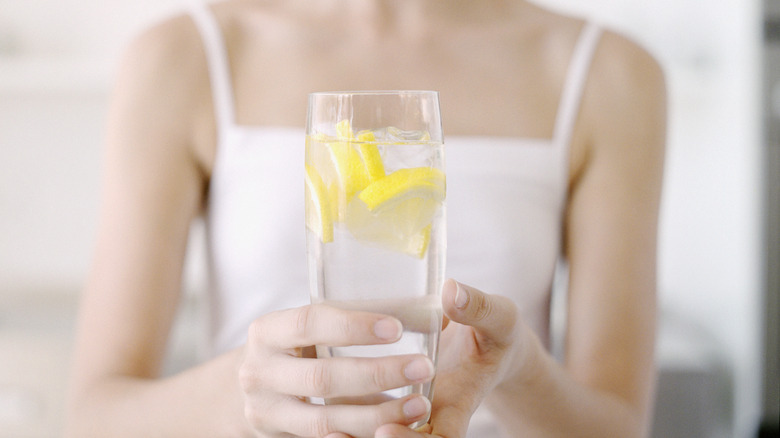 person holding glass of lemon water