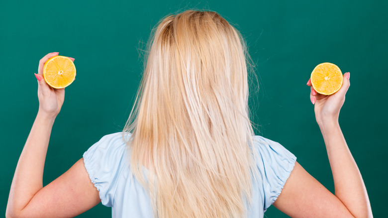 person with long blonde hair holding lemons