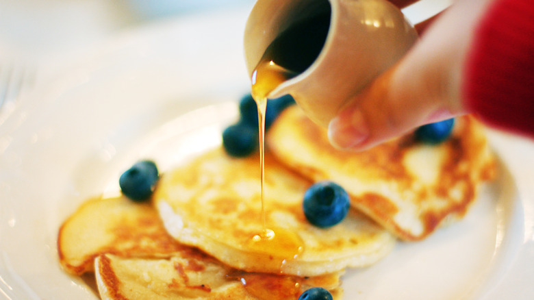 pouring syrup over pancakes