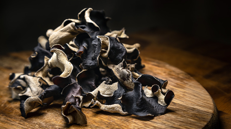 black dried mushrooms in a pile on a dark background