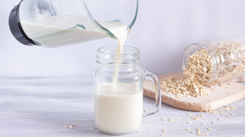 Pouring oats in blender into jar with oats in jar in background