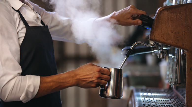 Barista steaming milk in machine