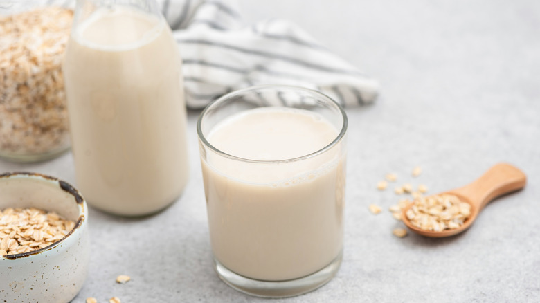 Oat milk on counter with container of oats and spoon