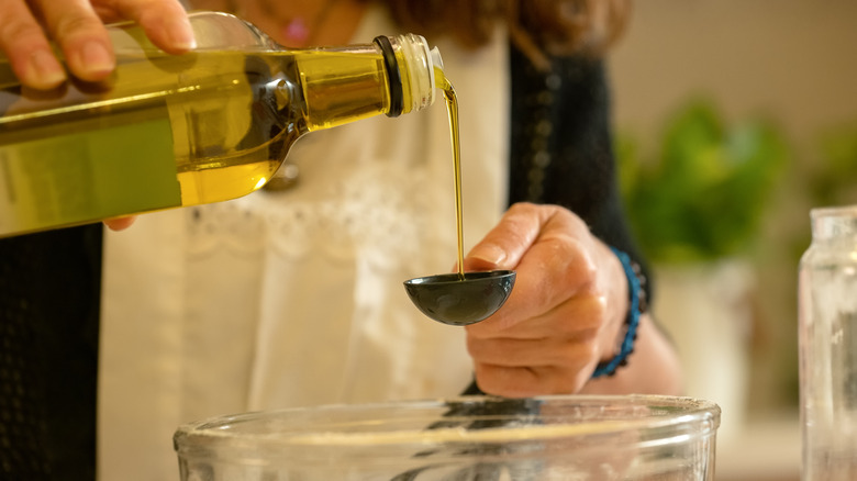 pouring oil into measuring spoon