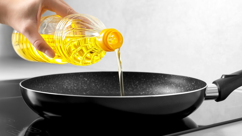 oil pouring into pan on cooktop