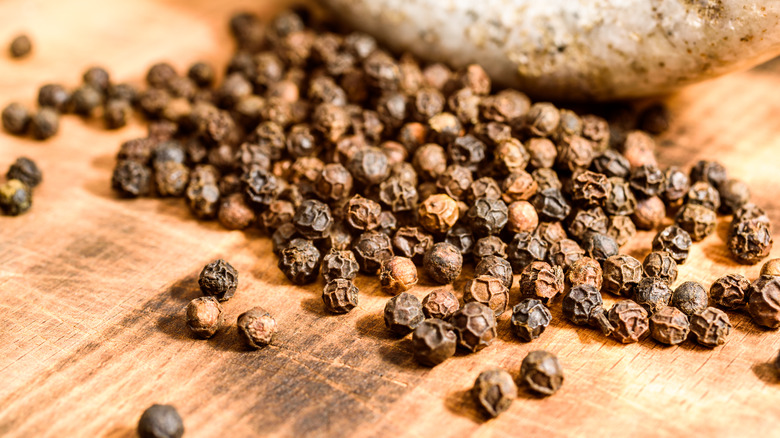 Tellicherry peppercorns on wooden counter